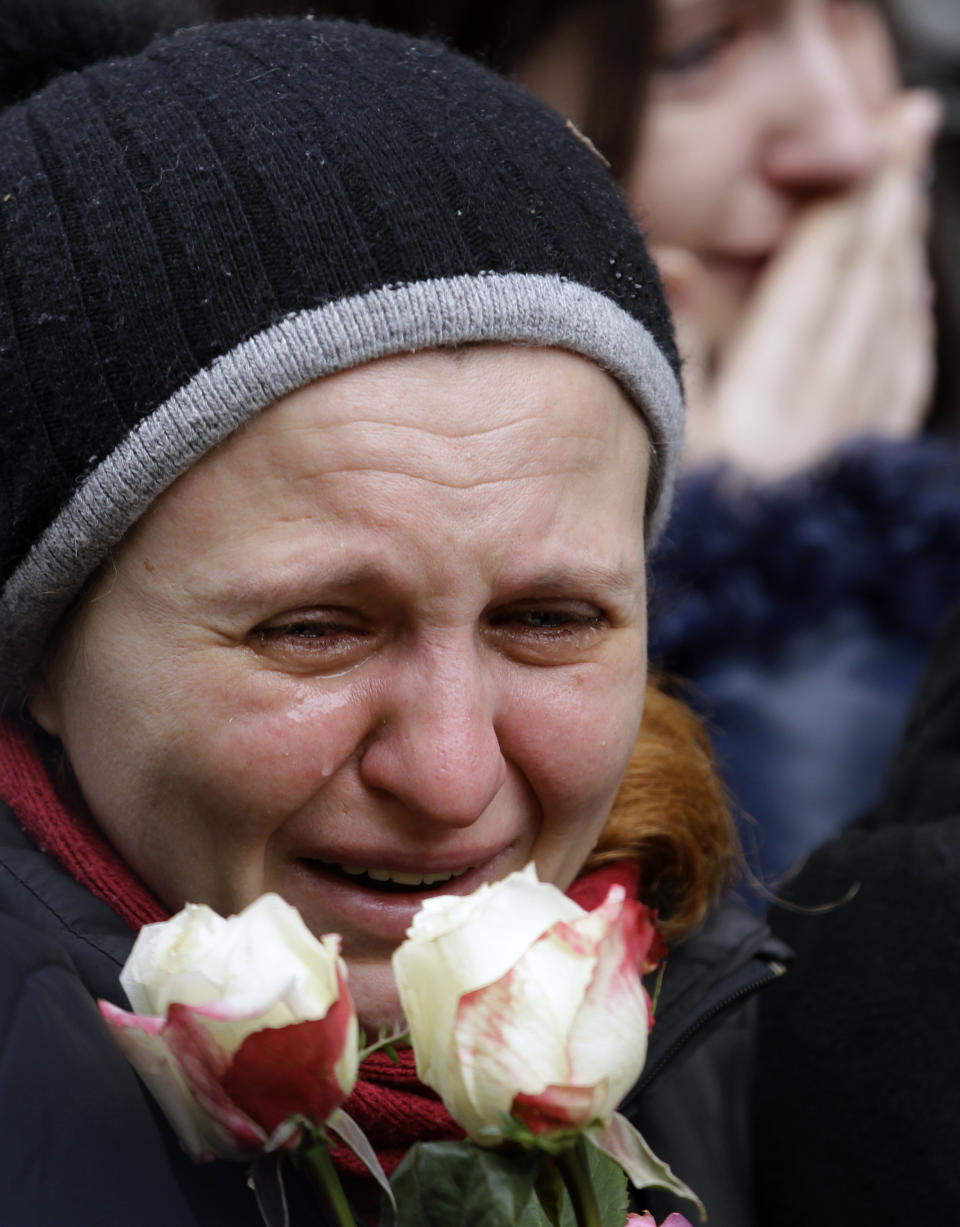 In this photo taken Saturday, Feb. 22, 2014, a woman cries during a commemorative service for Bogdan Solchunuk, 28, in front of the St. Paul and Peter church in Lviv, western Ukraine. If Ukraine looks neatly delineated on maps, its often-bloody history is a tangle of invasions and occupations, peoples and religions. It is a place that has been struggling for centuries to define itself. And now it finds itself so sharply divided _ between allegiance to Russia on one side of the country and loyalty to the West on the other _ that it often seems more like two countries than one. (AP Photo/Darko Vojinovic)