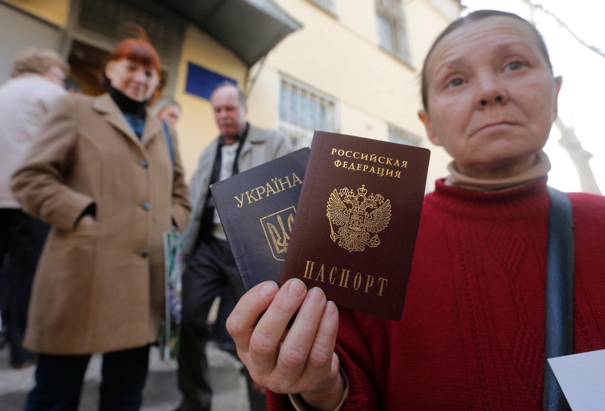 A woman poses with a Ukrainian and a Russian passport