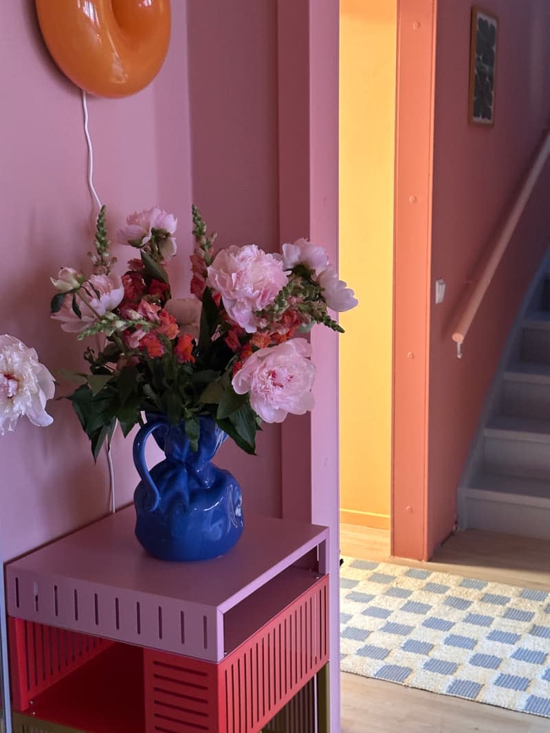 Flower arrangements are displayed on tables in the colorful hallway.