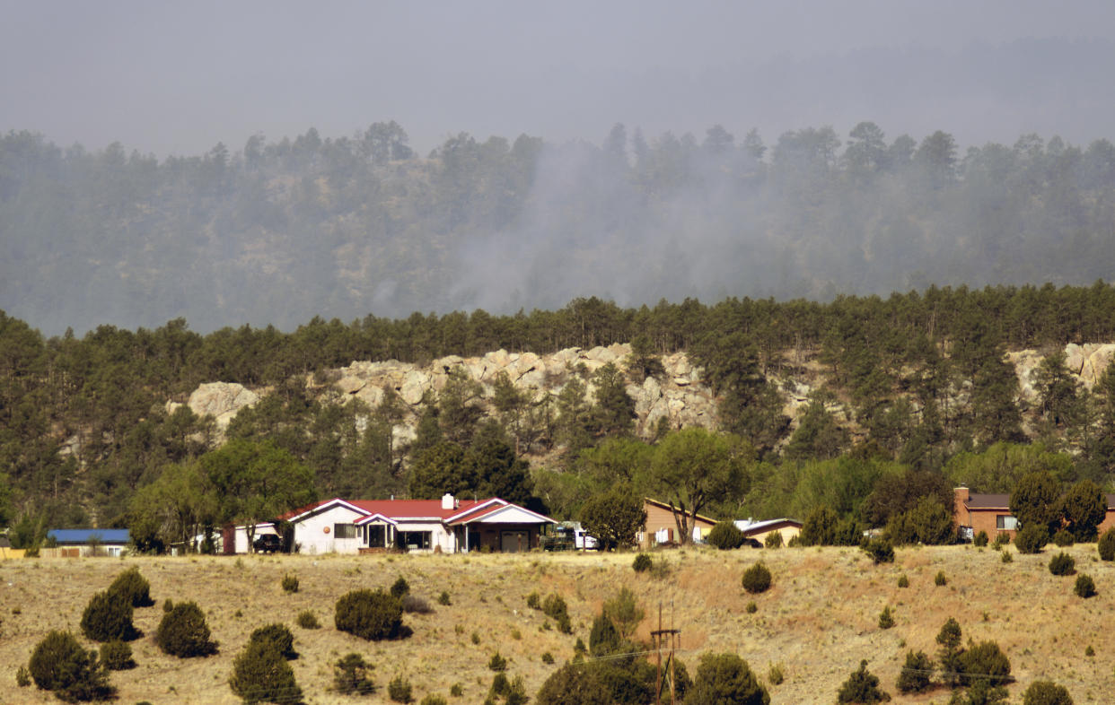 Smoke rises on a ridge behind homes on the outskirts of Las Vegas, N.M., on May 3, 2022. Flames raced across more of New Mexico's pine-covered mountainsides Tuesday, charring more than 217 square miles over the last several weeks. (AP Photo/Thomas Peipert)