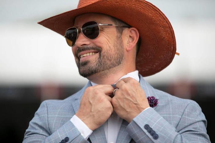 Brian Reynolds adjusts his boot at Churchill Downs in Louisville, Ky., Saturday, May 6, 2023.  He bought his burnt orange hat for the Kentucky Derby from a hat shop in Lexington.  Amy Wallot