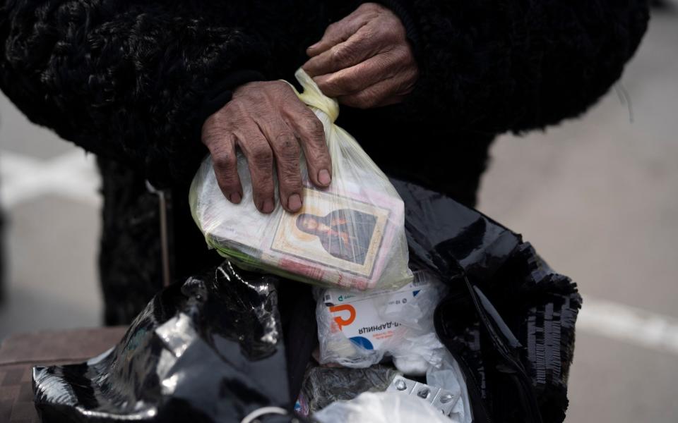 Valentina Greenchuck, 73, holds a plastic bag containing an orthodox icon after arriving from Mariupol at a refugee center in Zaporizhzhia, Ukraine - AP Photo/Leo Correa