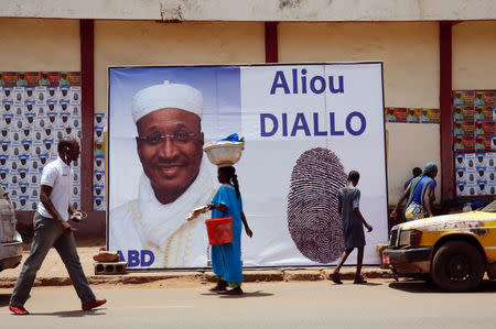 People walk past an election poster for opposition candidate Aliou Diallo, leader of the Democratic Alliance for Peace (Alliance Democratique pour la Paix, or ADP-MALIBA) Party, in Bamako, Mali July 26, 2018. REUTERS/Luc Gnago