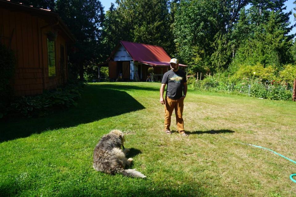 Andrew Clarke, one of the neighbors opposed to the Ranch Quarry Mine proposed off South Pass Road, stands on his property with his dog on Sept. 1, 2023, in Whatcom County, Wash. His property line borders the proposed quarry site.