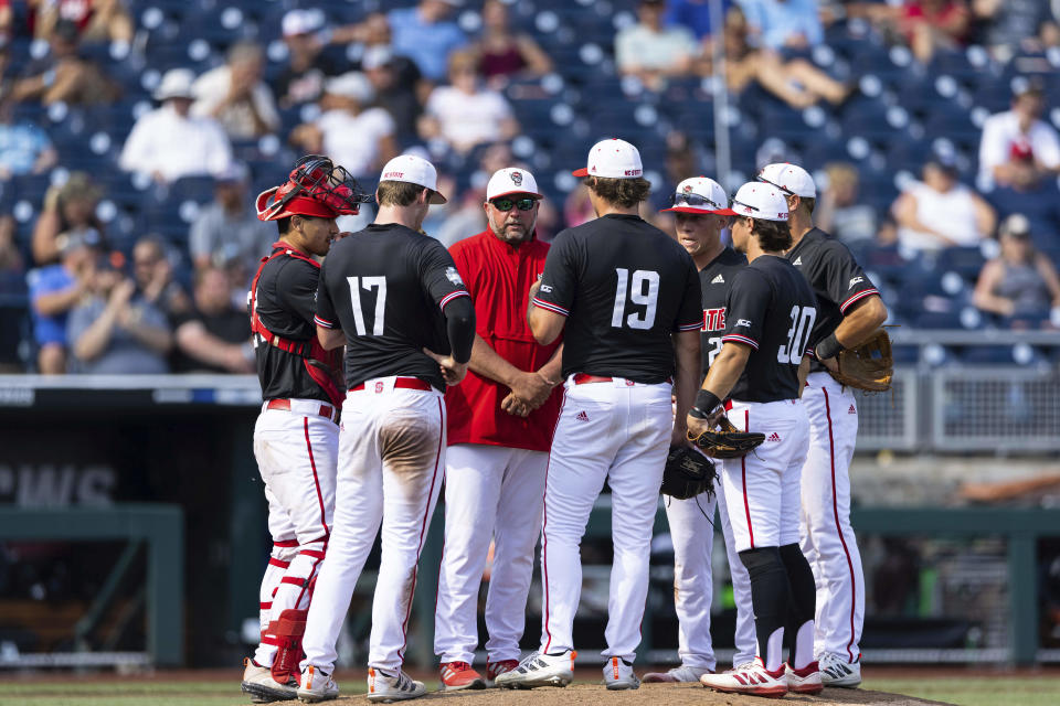 FILE - North Carolina State pitching coach Clint Chrysler, third from left, speaks with pitcher Dalton Feeney (19) during a meeting on the mound in the eighth inning against Vanderbilt during a baseball game in the College World Series Friday, June 25, 2021, at TD Ameritrade Park in Omaha, Neb. No return trip to the College World Series was ever promised when the 2021 Wolfpack were sent home by the NCAA amid a COVID-19 outbreak on the team. Four players from that team have made it back, and they're savoring every moment. The Wolfpack play Kentucky in their opener Saturday. (AP Photo/Rebecca S. Gratz, File)