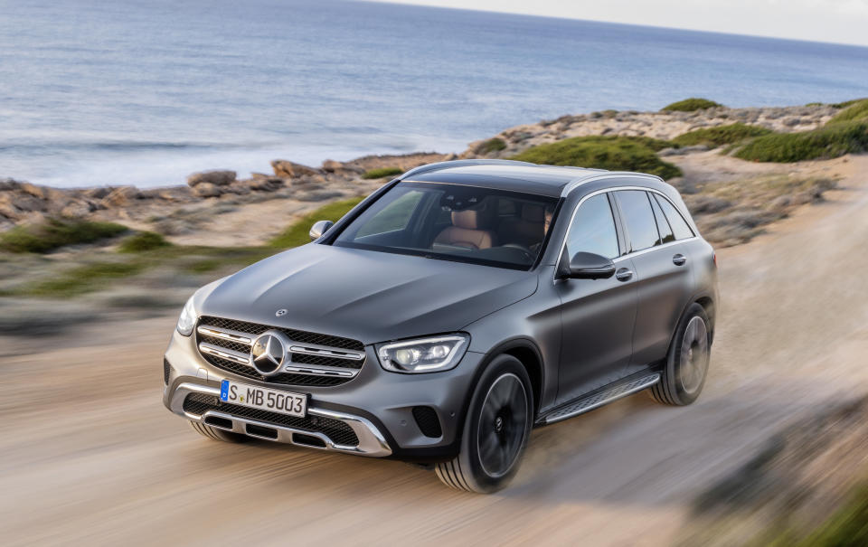 A dark gray 2019 Mercedes-Benz GLC, a small luxury crossover SUV, on a dirt road near a waterfront.