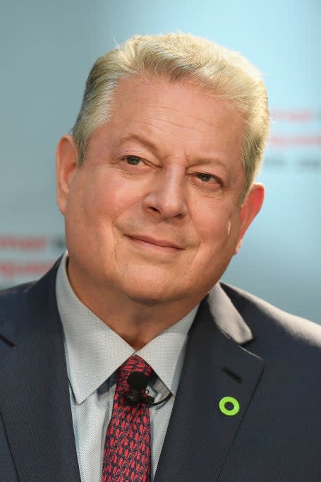 Al Gore in a suit with a lapel pin, smiling at an event