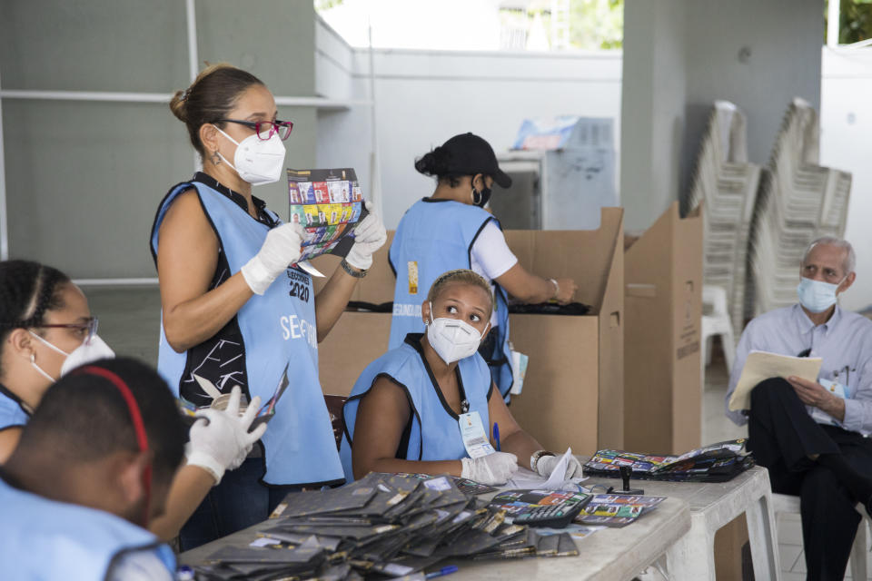 Electoral officials wear protective masks as a precaution against the spread of the new coronavirus, while counting ballots after polls closed during the presidential elections, in Santo Domingo, Dominican Republic, Sunday, July 5, 2020. (AP Photo/Tatiana Fernandez)