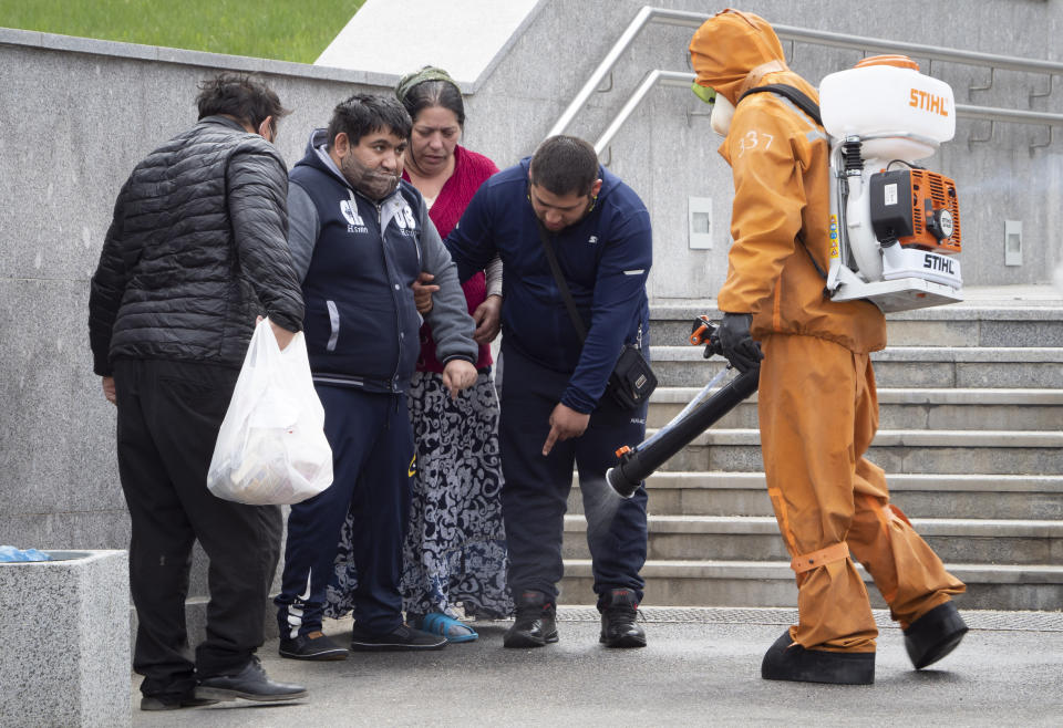 A Russian Emergency Situation worker disinfects people leaving a hospital near the scene of a fire at St. George Hospital in St. Petersburg, Russia, Tuesday, May 12, 2020. A fire at St. George Hospital has killed five coronavirus patients. Russian emergency officials said all five had been put on ventilators. The emergency officials told the state Tass new agency the fire broke out in an intensive care unit and was put out within half an hour. (AP Photo/Dmitry Lovetsky)