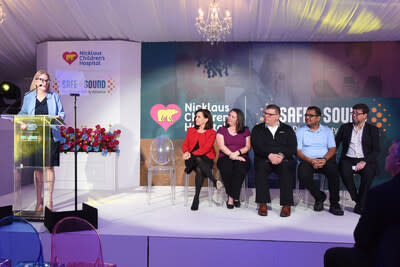 Jennifer McCafferty-Fernandez, PhD, of Nicklaus Children's Health System welcomes guests during the launch of the Nicklaus Children’s Safe + Sound digital safety initiative. On stage (left to right): Marisa Azaret, PsyD, Nicklaus Children’s;  Michelle Appelrouth-Rader, Nicklaus Children’s Family Advisory Council member; Bill Brady, Troomi Wireless; Lokesh Ramamoorthi, University of Miami; Lee Phillips, Digital Health Institute for Transformation.