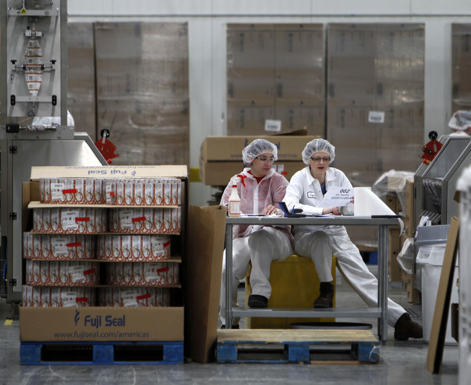 FILE -- In this Jan. 13, 2012 file photo, two women work in the sleeving plant where labels are put on containers at Chobani Greek Yogurt in South Edmeston, N.Y. Team USA sponsor Chobani, which is based in upstate New York, says it has 5,000 cups of Greek yogurt sitting in a refrigerated warehouse waiting to be flown to the Olympic village. But Russian authorities say the U.S. Department of Agriculture has refused to provide a certificate that is required for dairy products under its customs rules. A U.S. Department of Agriculture spokeswoman says the agency is working with its Russian counterpart to reach a solution to allow the Chobani shipment to go through despite the lack of agreement on general trade requirements for dairy products.(AP Photo/Mike Groll, File)