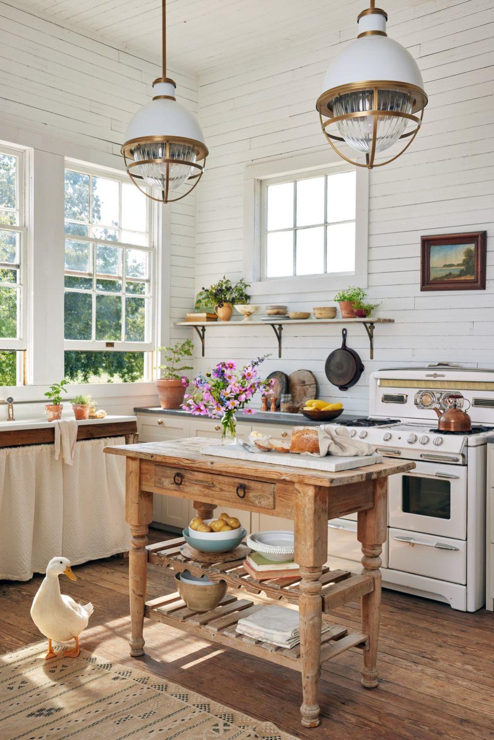 a tiny farmhouse kitchen packed with charm like a skirted sink and open shelving and a pine island and a vintage stove