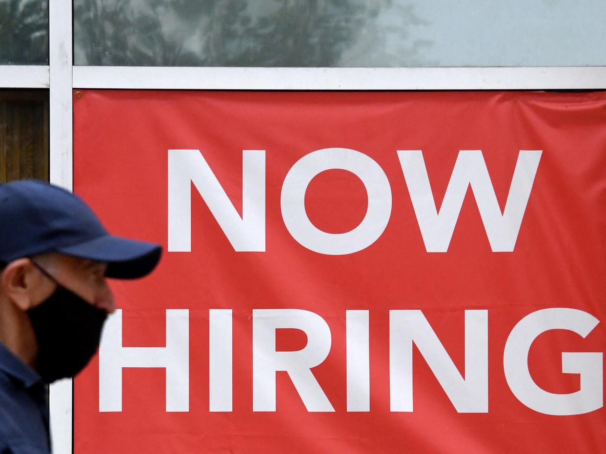 A man walks by a "Now Hiring" sign outside a store on August 16, 2021 in Arlington, Virginia.