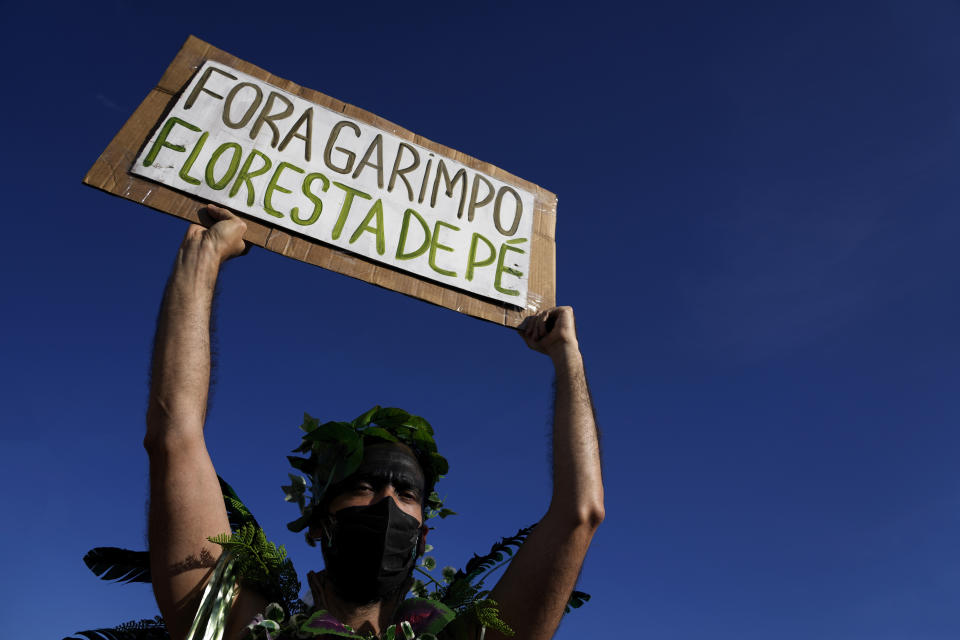 FILE - An activist holds a sign written in Portuguese that reads "Mining out. The forest stands," during a demonstration by the "Act for the Earth" movement in front of the National Congress in Brasilia, Brazil, March 9, 2022. The two-day Amazon Summit opens Tuesday, Aug. 8, 2023, in Belem, where Brazil hosts policymakers and others to discuss how to tackle the immense challenges of protecting the Amazon and stemming the worst of climate change. (AP Photo/Eraldo Peres, File)