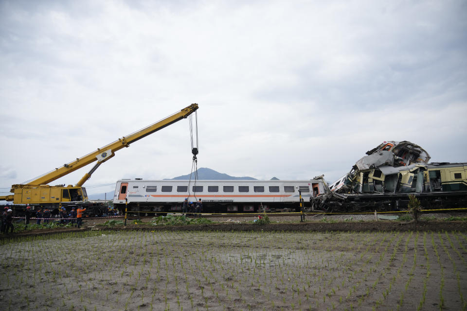 A crane tries to remove the wreckage after the collision between two trains in Cicalengka, West Java, Indonesia, Friday, Jan. 5, 2024. The trains collided on Indonesia's main island of Java on Friday, causing several carriages to buckle and overturn, officials said. (AP Photo/Achmad Ibrahim)