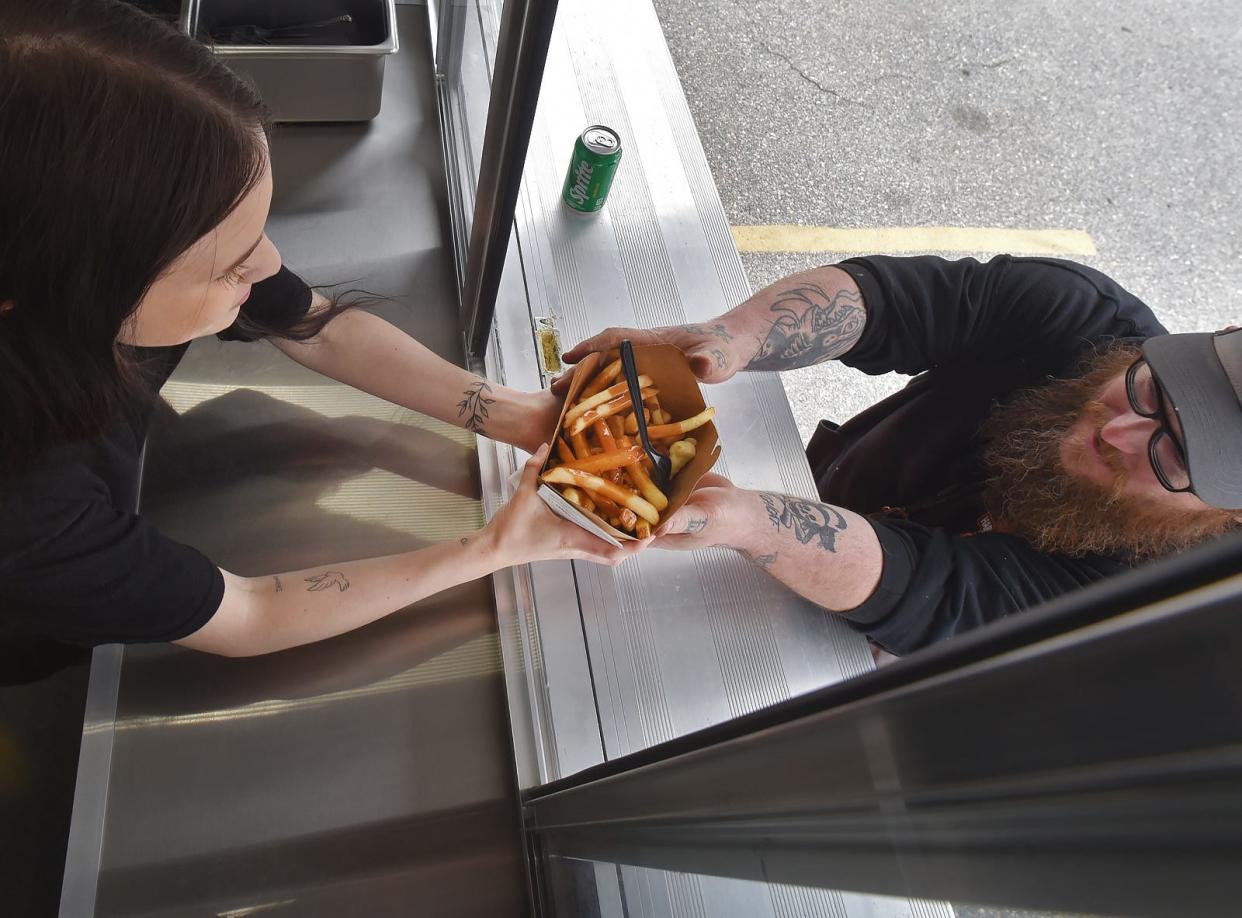 Crew member Meela Farias hands an order of Poutine to a customer at the Krave Poutinerie at 486 Bedford St. in Fall River Friday May 3 2024.