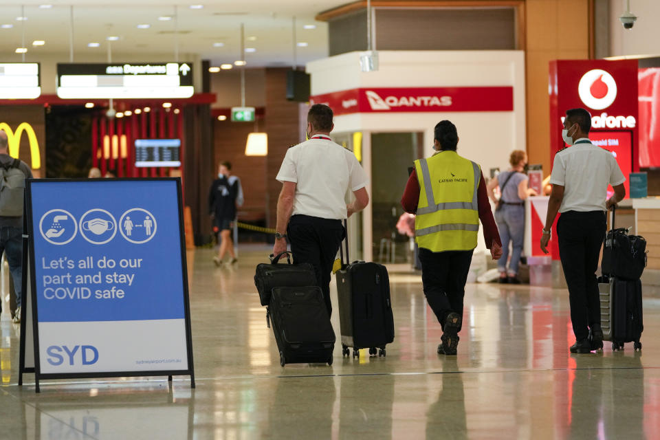 A flight crew walk through the terminal at Sydney Airport, Monday, Nov. 29, 2021. Authorities in Australia said Sunday, Nov. 28, 2021, that two travelers who arrived in Sydney from Africa became the first in the country to test positive for the new variant of the coronavirus, omicron. (AP Photo/Mark Baker)