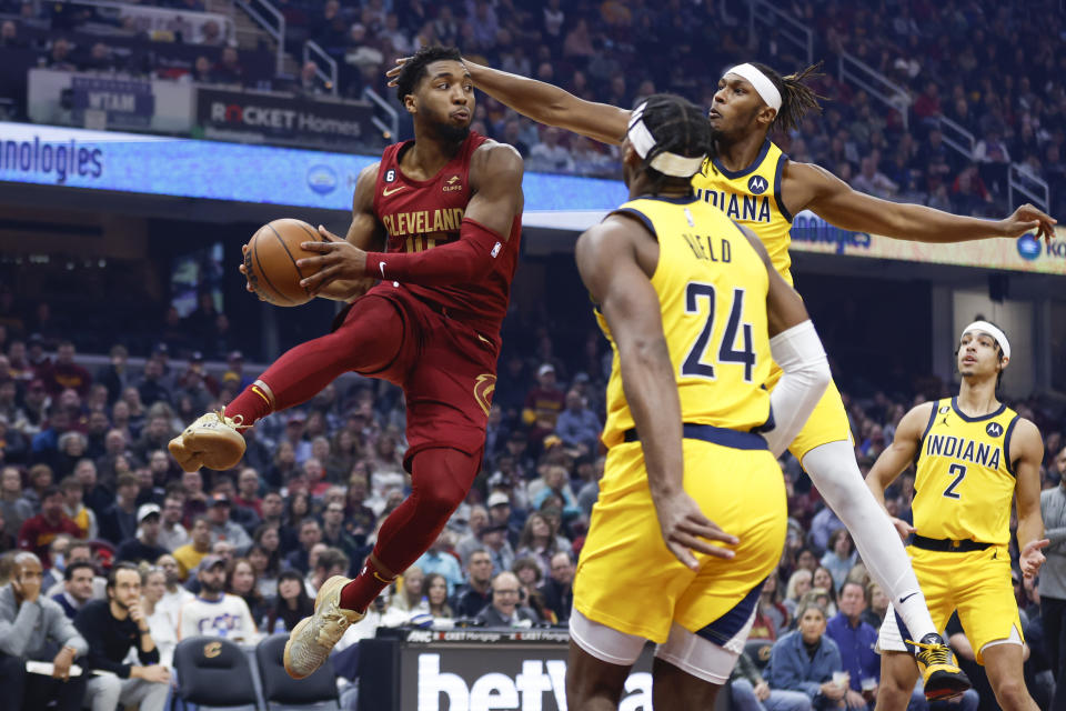 Cleveland Cavaliers guard Donovan Mitchell (45) passes against Indiana Pacers guard Buddy Hield (24) and center Myles Turner (33) during the first half of an NBA basketball game, Friday, Dec. 16, 2022, in Cleveland. (AP Photo/Ron Schwane)