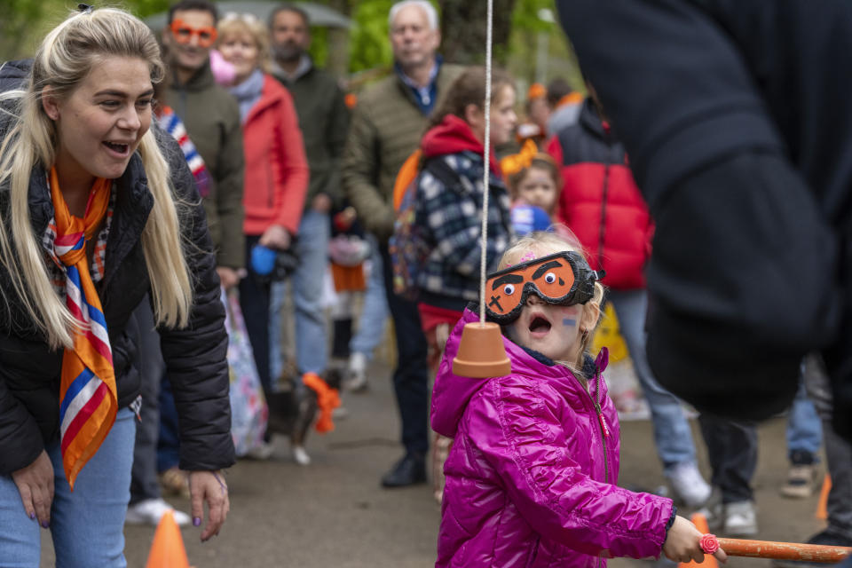 A blindfolded child attempts to hit a flowerpot as she plays a game during King's Day celebrations in Amsterdam, Netherlands, April 27, 2024. (AP Photo/Peter Dejong)