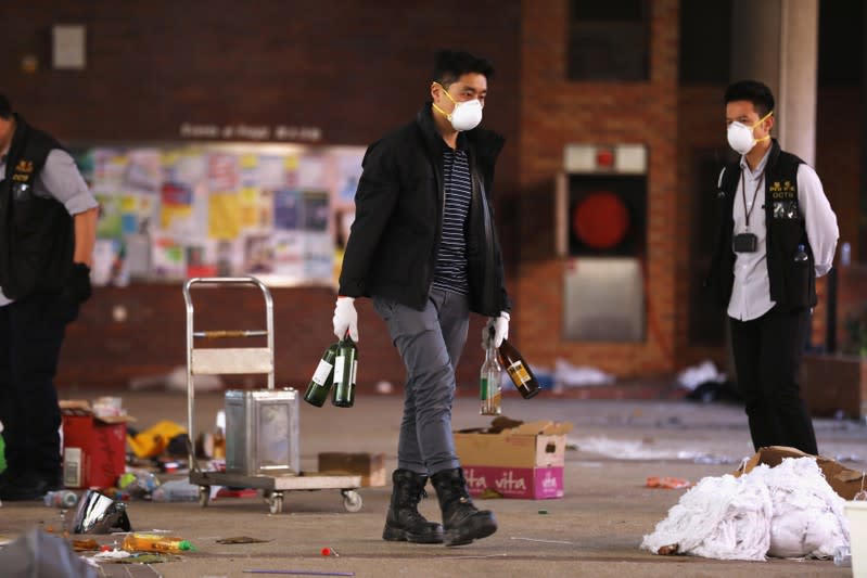 Police and firefighting personnel move Molotov cocktails, flammable materials and liquids into a corner, inside the Hong Kong Polytechnic University (PolyU) in Hong Kong, China