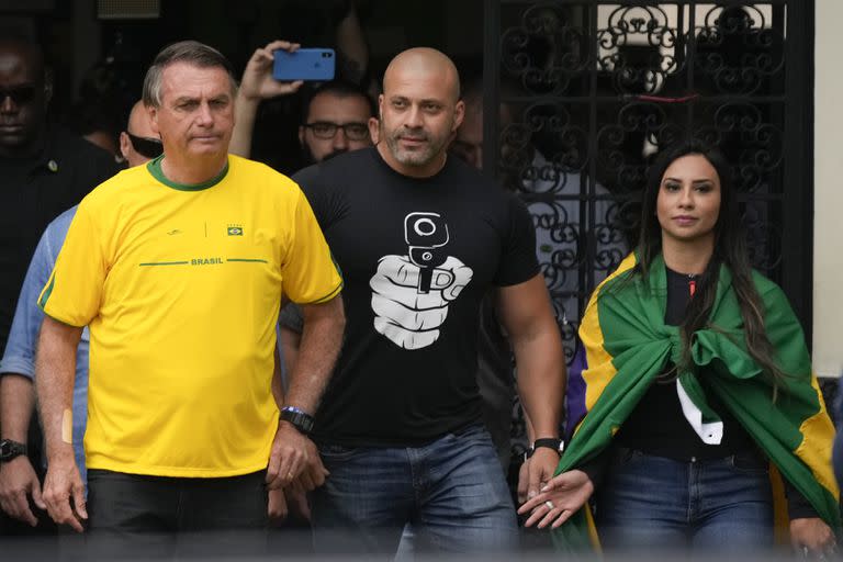 El presidente brasileño Jair Bolsonaro, a la izquierda, que se postula para otro mandato, sale de un centro de votación después de votar durante las elecciones generales en Río de Janeiro, Brasil, el domingo 2 de octubre de 2022