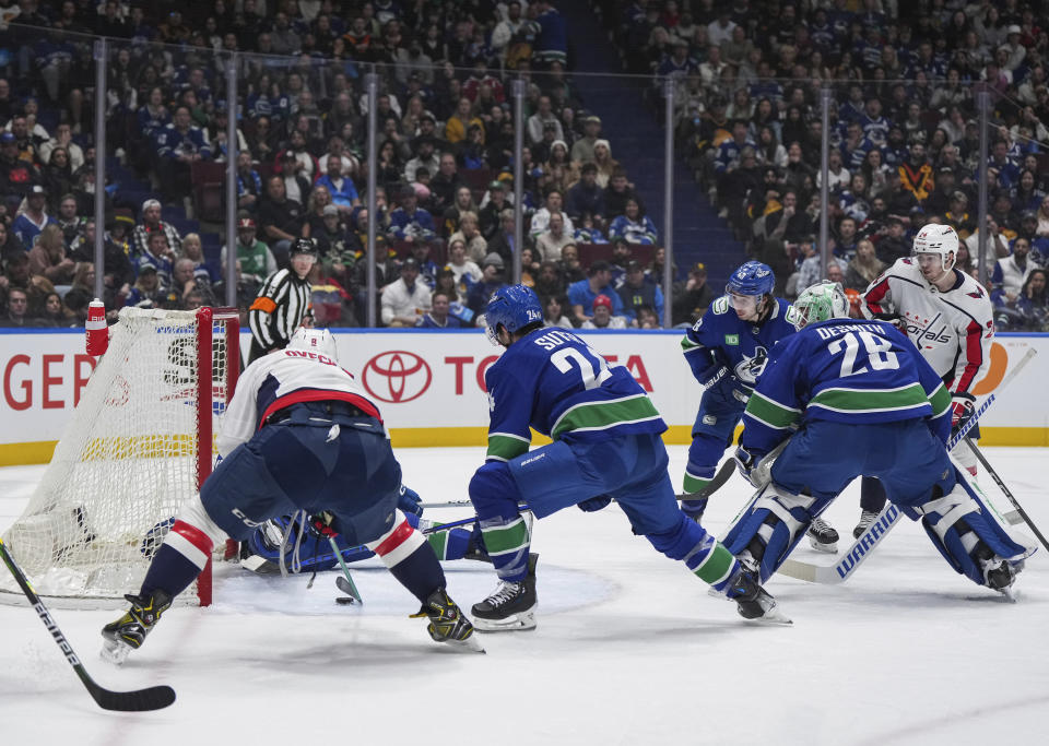 Washington Capitals' Alex Ovechkin, front left, scores as Vancouver Canucks' Pius Suter (24), goalie Casey DeSmith (29), Quinn Hughes (43) and Washington's Connor McMichael, back right, watch during the second period of an NHL hockey game in Vancouver, British Columbia, Saturday, March 16, 2024. (Darryl Dyck/The Canadian Press via AP)