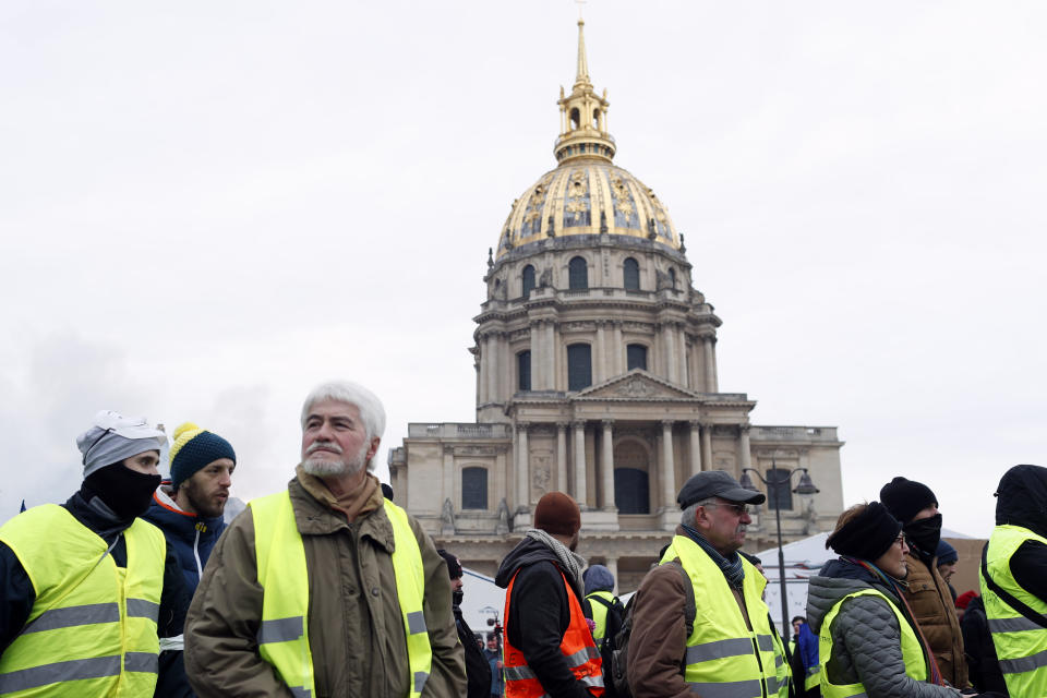 Yellow vest protesters march past the Invalides monument Saturday, Jan. 19, 2019 in Paris. Yellow vest protesters are planning rallies in several French cities despite a national debate launched this week by President Emmanuel Macron aimed at assuaging their anger. (AP Photo/Thibault Camus)