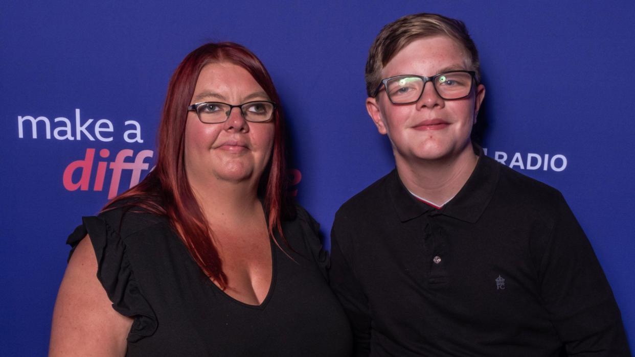 A woman and a boy, both wearing glasses, pose for the camera