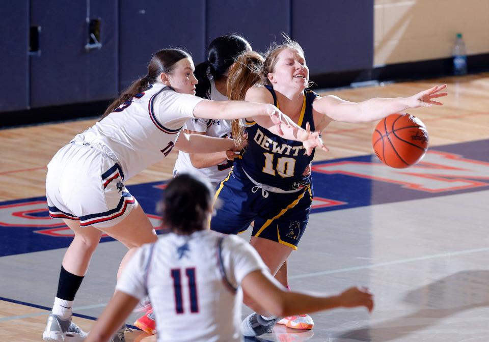 DeWitt's Madi Uyl, right, is fouled as she is pressured by East Lansing's Sophie Klinger, left, and Nevaeh Vasquez, Friday, Jan. 19, 2024, in East Lansing. DeWitt won 61-49.