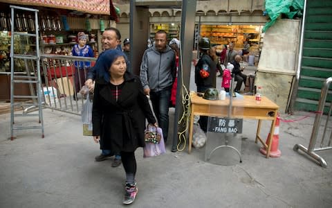 In this Nov. 4, 2017 photo, residents past through one of the many security check points in Kashgar in western China's Xinjiang region - Credit: Ng Han Guan/ AP