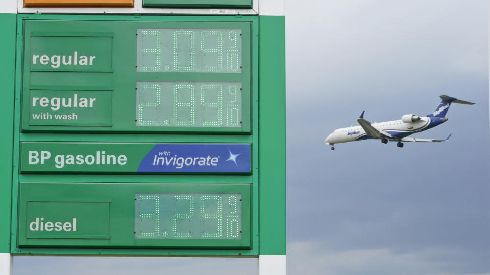 FILE - In this May 26, 2021 file photo, gas prices are displayed as a jet descends to land at Cleveland Hopkins International Airport in Cleveland. Americans were hitting the road in near-record numbers at the start of the holiday weekend. More than 1.8 million people went through U.S. airports on Thursday, and that number could top 2 million over the weekend, the highest mark since early March of last year. (AP Photo/Tony Dejak, File)
