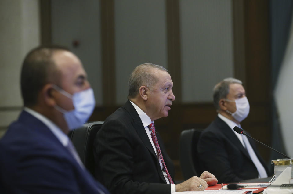 Turkey's President Recep Tayyip Erdogan, center, is flanked by Defence Minister Hulusi Akar, right, and Foreign Minister Mevlut Cavusoglu during a video conference with Russia's President Vladimir Putin and Iran's President Hassan Rouhani, in Ankara, Turkey, Wednesday, July 1, 2020. In his opening remarks to the three-way summit between the Turkish, Iranian and Russian leaders, Erdogan said the three countries' aim was to protect Syria's political and territorial unity, to end the fighting on the ground and to find a political solution to the conflict.(Presidential Press Service via AP, Pool)