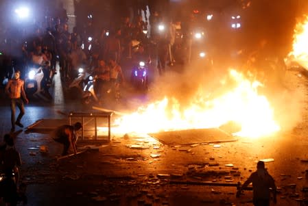 Demonstrators on motorbikes ride close to a fire during a protest over deteriorating economic situation in Beirut