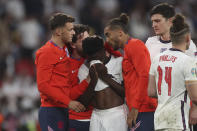 FILE - England players comfort teammate Bukayo Saka after he failed to score a penalty during a penalty shootout after extra time during of the Euro 2020 soccer championship final match between England and Italy at Wembley stadium in London, Sunday, July 11, 2021. The manifestation of a deeper societal problem, racism is a decades-old issue in soccer — predominantly in Europe but seen all around the world — that has been amplified by the reach of social media and a growing willingness for people to call it out. (Carl Recine/Pool Photo via AP, File)