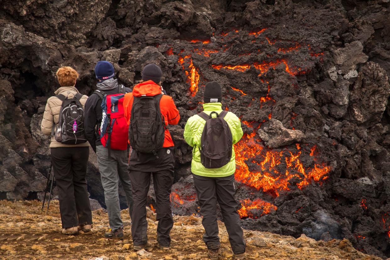 People watch the Lava flows from an eruption of a volcano on the Reykjanes Peninsula in southwestern Iceland on Wednesday, March 31, 2021. Iceland's latest volcano eruption is still attracting crowds of people hoping to get close to the gentle lava flows.