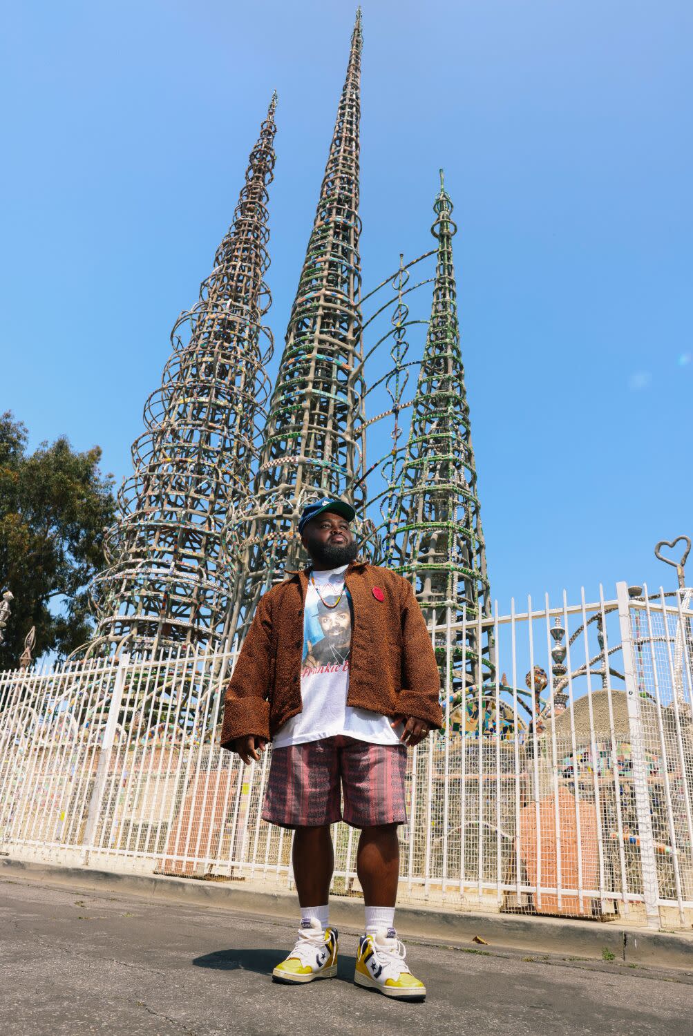 A man stands in front of the Watts Towers.