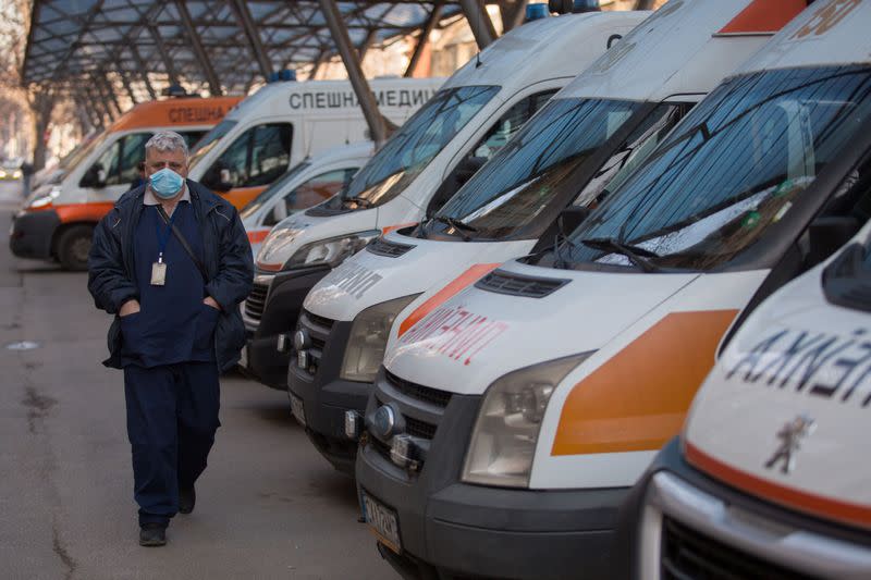 A medical worker wearing a mask passes by an ambulance at Sofia emergency center in Sofia