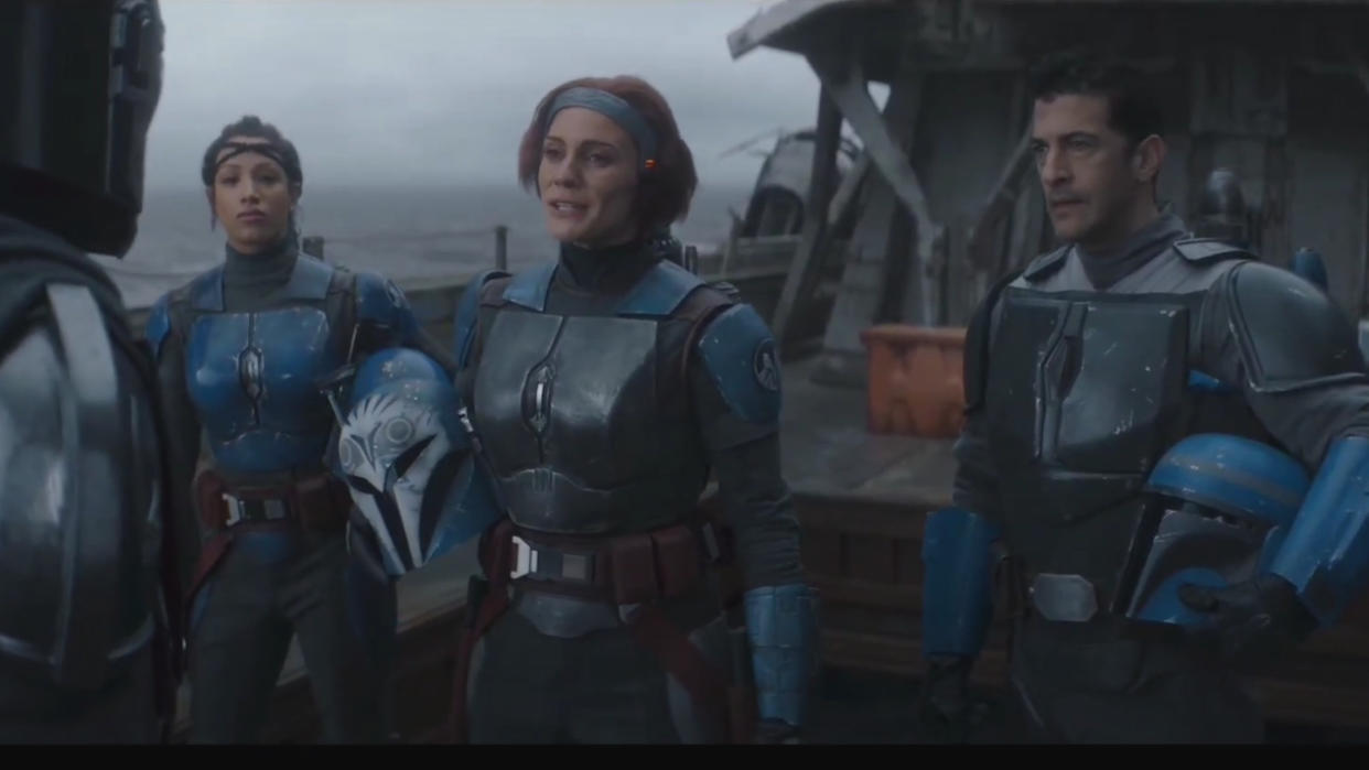  Sasha Banks, Katee Sackhoff, and Simon Kassianides stand on a ship together in The Mandalorian.  