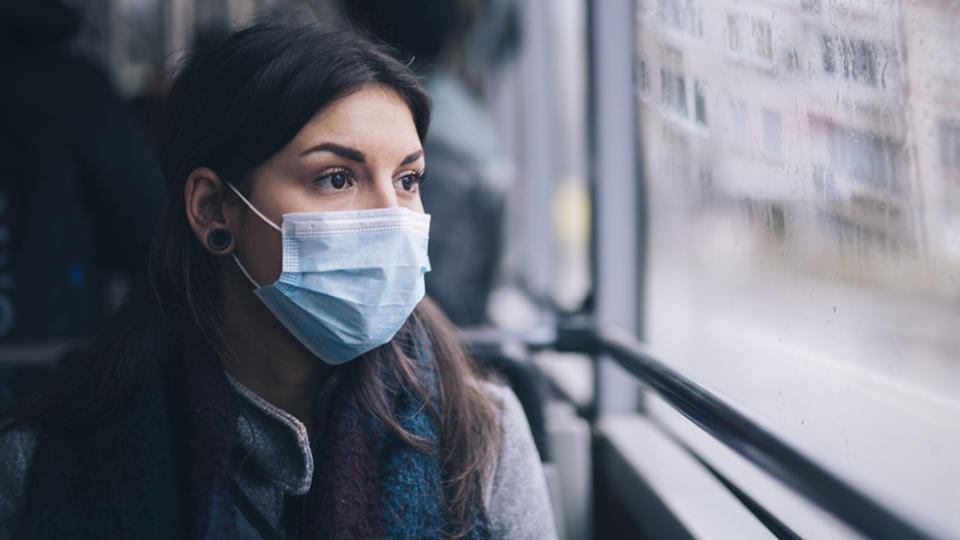 Woman wearing a surgical mask on public transport to protect herself from coronavirus