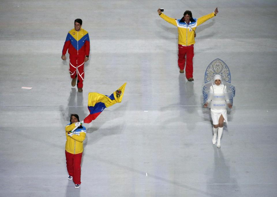 Antonio Pardo of Venezuela holds his national flag and enters the arena with his teammates during the opening ceremony of the 2014 Winter Olympics in Sochi, Russia, Friday, Feb. 7, 2014. (AP Photo/Charlie Riedel)