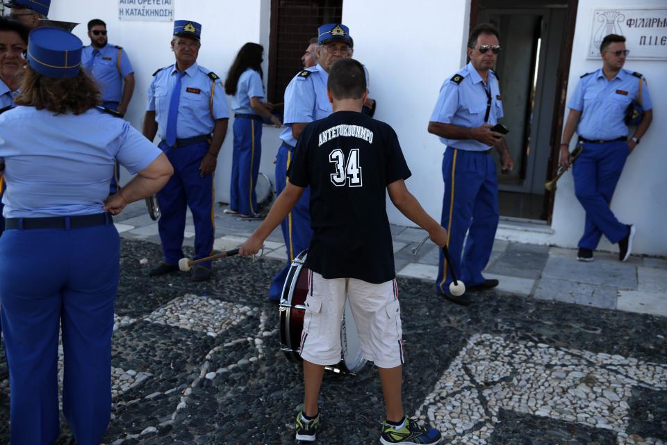 A boy plays with the drumsticks as the Philharmonic band stands outside the Holy Church of Panagia of Tinos, on the Aegean island of Tinos, Greece, on Thursday, Aug. 13, 2020. For nearly 200 years, Greek Orthodox faithful have flocked to Tinos for the August 15 feast day of the Assumption of the Virgin Mary, the most revered religious holiday in the Orthodox calendar after Easter. But this year there was no procession, the ceremony _ like so many lives across the globe _ upended by the coronavirus pandemic. (AP Photo/Thanassis Stavrakis)