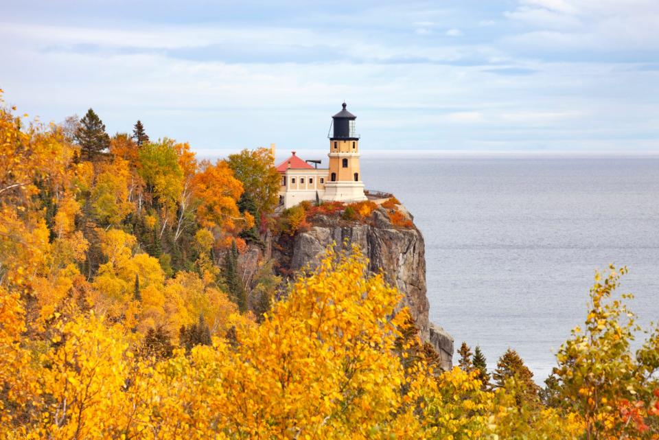 Lighthouse on edge of cliff surrounded by sea and yellow foliage in Minnesota