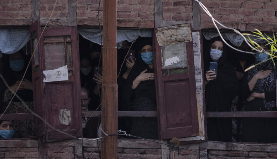 Kashmiri Shiite Muslims wearing face masks watch a Muharram procession from a residential house in Srinagar, Indian controlled Kashmir, Saturday, Aug. 29, 2020. Muharram is a month of mourning in remembrance of the martyrdom of Imam Hussein, the grandson of Prophet Mohammed. Authorities had imposed restrictions in parts of Srinagar, the region's main city, to prevent gatherings marking Muharram from developing into anti-India protests. (AP Photo/Mukhtar Khan)