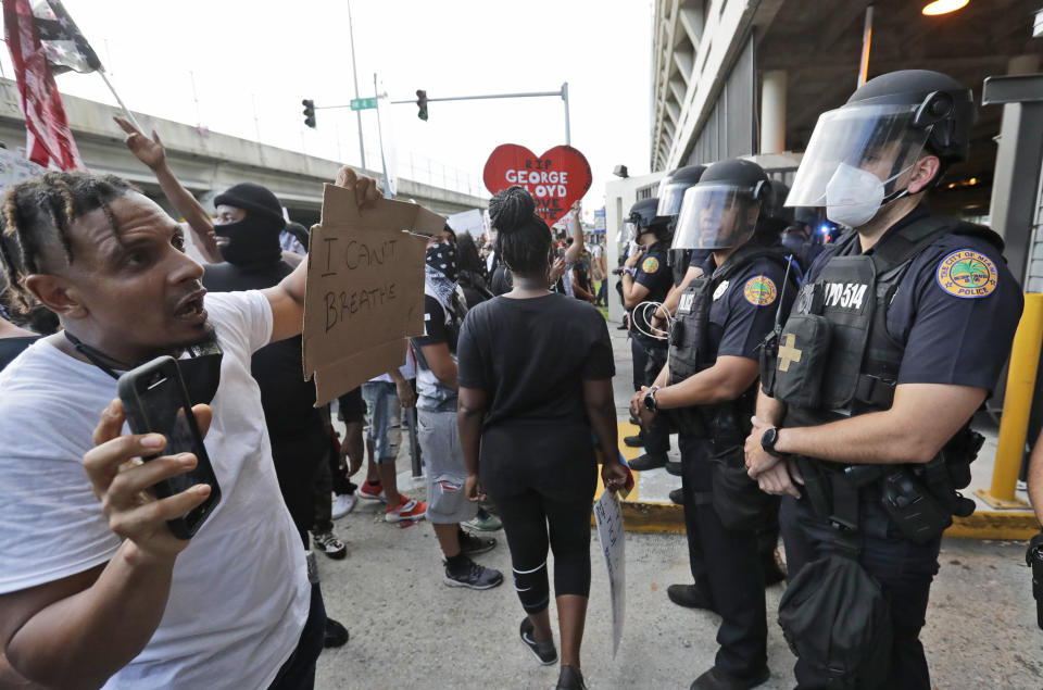 A protester confronts a line of police during a demonstration next to the city of Miami Police Department, Saturday, May 30, 2020, downtown in Miami. Protests were held throughout the country over the death of George Floyd, a black man who died after being restrained by Minneapolis police officers on May 25.(AP Photo/Wilfredo Lee)