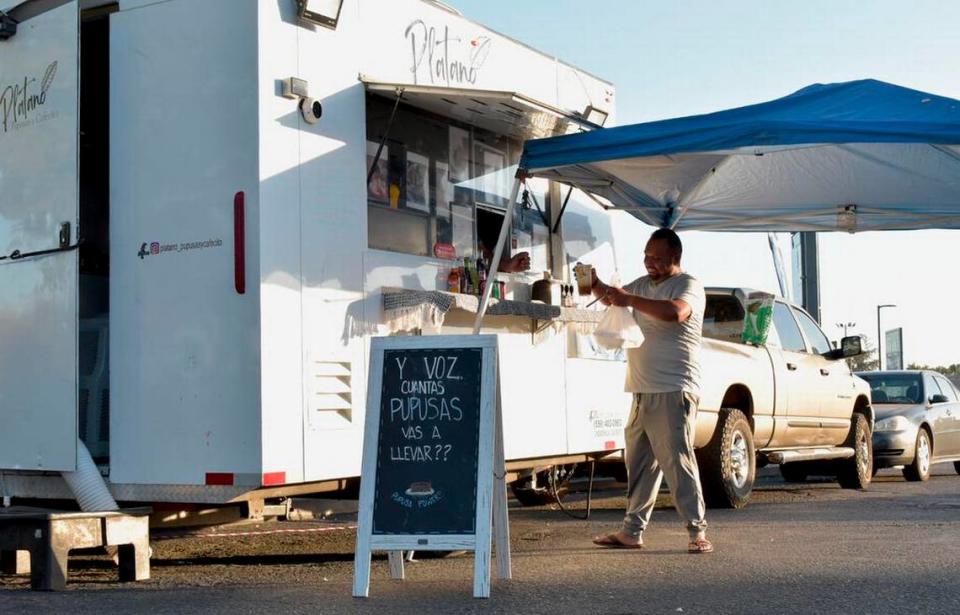 Un hombre recibe su pedido en Plátano, Pupusas y Cafecito en Madera, el 7 de octubre. El remolque de comida salvadoreña opera en el lote de una gasolinera Chevron en Cleveland Avenue y Highway 99 en la ciudad de Madera, donde los propietarios dicen que podrían terminar quedándose a pesar de ser habitantes de Chowchilla.