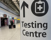 Travellers walk towards the Covid-19 testing centre at Heathrow Airport in London, Sunday, Jan. 17, 2021. The UK will close all travel corridors from Monday morning to protect against the coronavirus with travellers entering the country from overseas are required to have proof of a negative Covid test. (AP Photo/Frank Augstein)