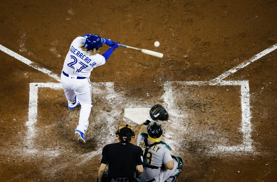 Toronto Blue Jays rookie Vladimir Guerrero Jr. (27) hits a fly ball off Oakland Athletics' Josh Phegley during the sixth inning of baseball game action in Toronto, Friday, April 26, 2019. (Mark Blinch/The Canadian Press via AP)