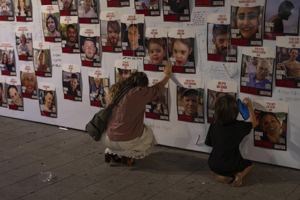 FILE - A woman touches photos of Israelis missing and held captive in Gaza, displayed on a wall in Tel Aviv, on Saturday, Oct. 21, 2023. One of the missing, Ohad Munder-Zichri, turned 9 on Monday. But instead of celebrating at home with his family and friends, he was somewhere in Gaza, one of more than 200 Israelis held hostage by Hamas since their devastating Oct. 7 incursion. (AP Photo/Petros Giannakouris, File)