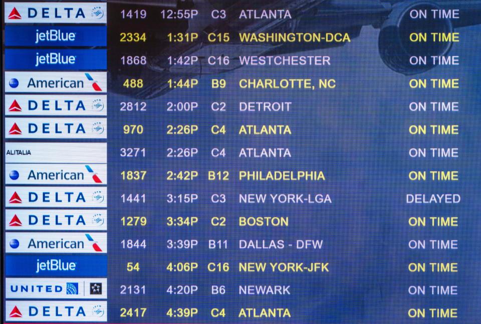 A monitor shows the status for departing flights Friday from Palm Beach International Airport.