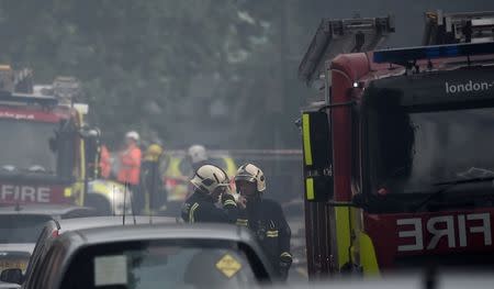 Firefighters stand near a fire at a low-rise block of buildings in Bethnal Green, northeast London, Britain, June 24, 2017. REUTERS/Hannah McKay